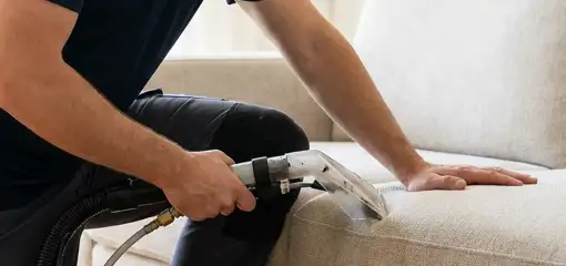 Professional upholstery cleaner deep-cleaning a fabric sofa with a handheld extraction tool, Charlotte, NC.